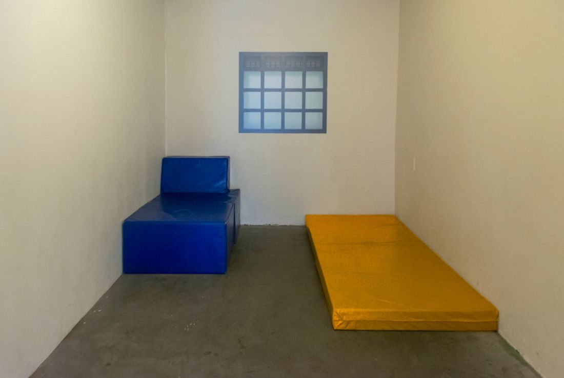 A small room with a blue chair and a low yellow seat.