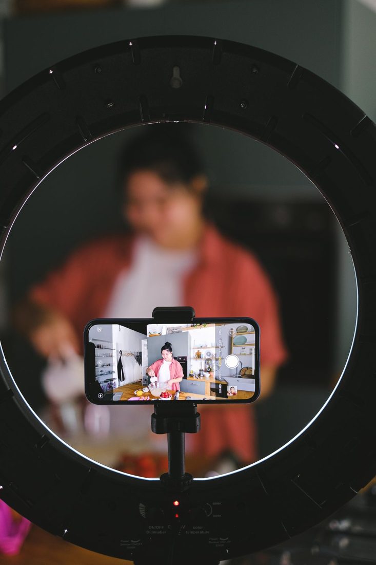 A phone and ring light recording a person cooking.