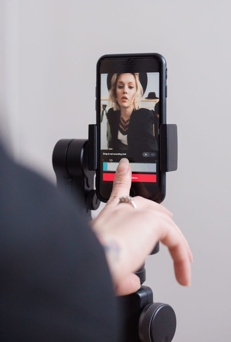 A hand adjusting a phone showing a woman's portrait video.