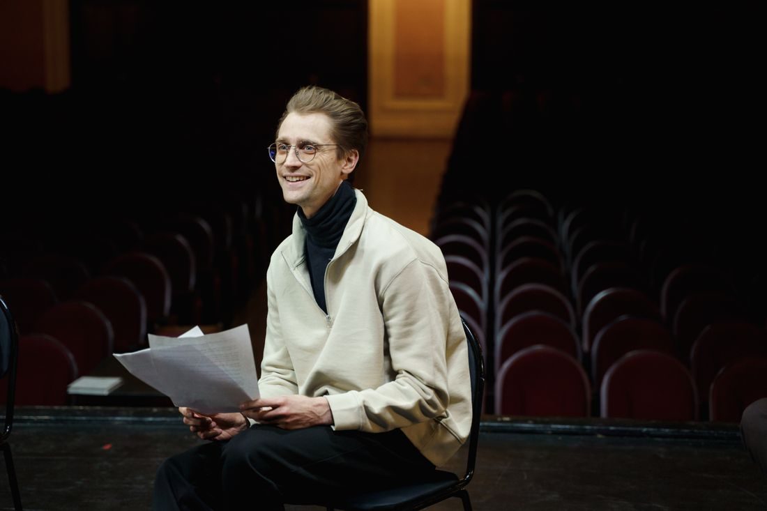 A man holding a script in an empty auditorium.