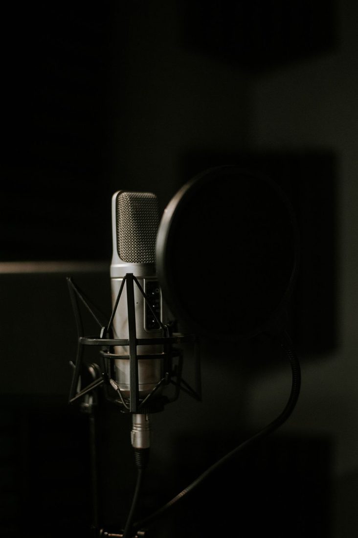 A microphone and pop filter in a dim recording space.