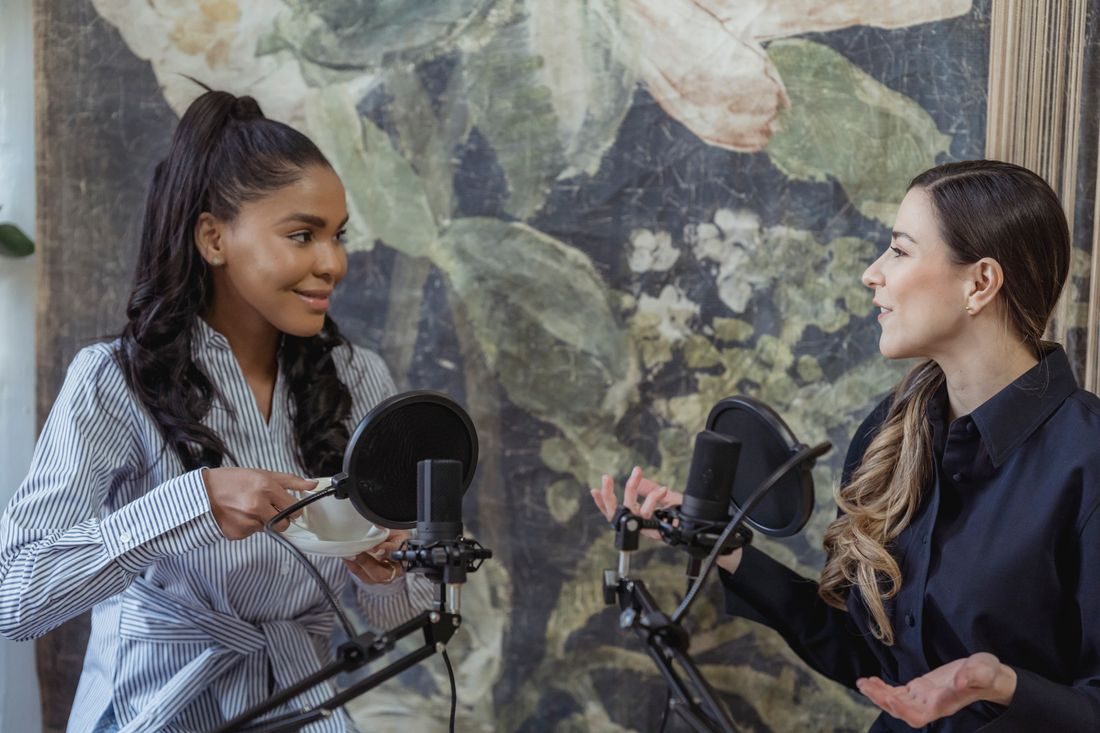 Two women seated with separate microphones and headphones.
