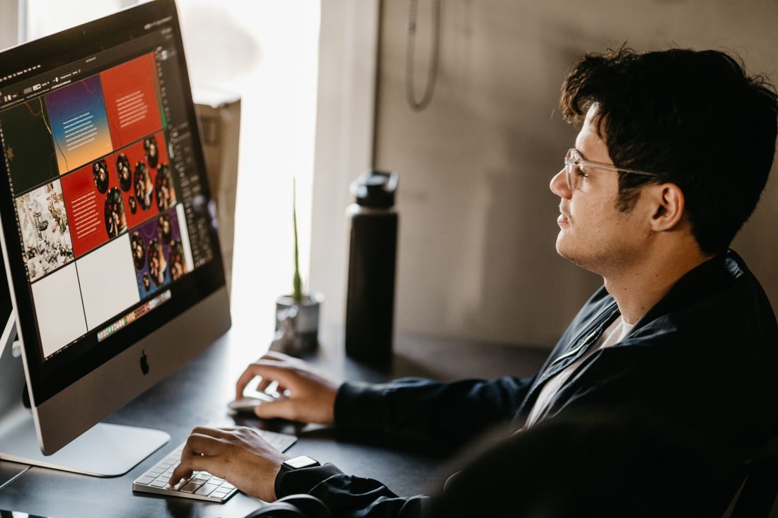 A designer working on a screen displaying a graphic layout.