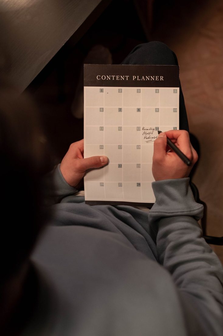 Hands marking dates on a content planning calendar.