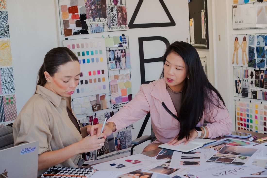 Two people discussing creative work and printed materials.